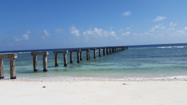 A series of pylons stretch out into the water, marking the location of a former pier.