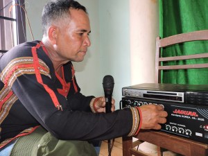  Từ sáng sớm, ông Mae (58 tuổi), ban công tác mặt trận Buôn K’Nia 4 thông báo cử tri ở buôn cầm lá phiếu đi bầu cử tại nhà văn hoá.