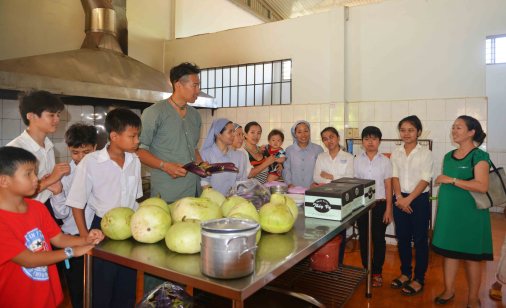 Chị Minh áo xanh phiên dịch lời anh Takano Yukino tặng quà cho các cháu khuyết tật