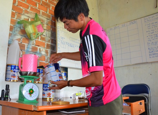 Ninh cẩn thận cân sữa để pha cho voi