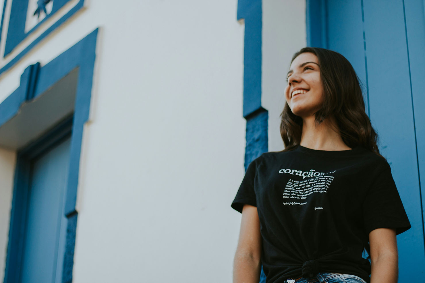 A young woman with brown hair smiles, looking upwards. She's wearing a black shirt.